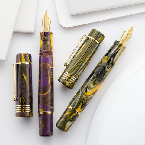 Delta Neo Gallery fountain pens in purple yellow marbled acrylic with gold nibs on a light background
