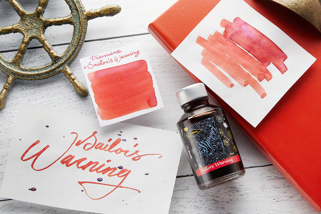Sailors Warning ink bottle, writing sample, and swab on white wood background