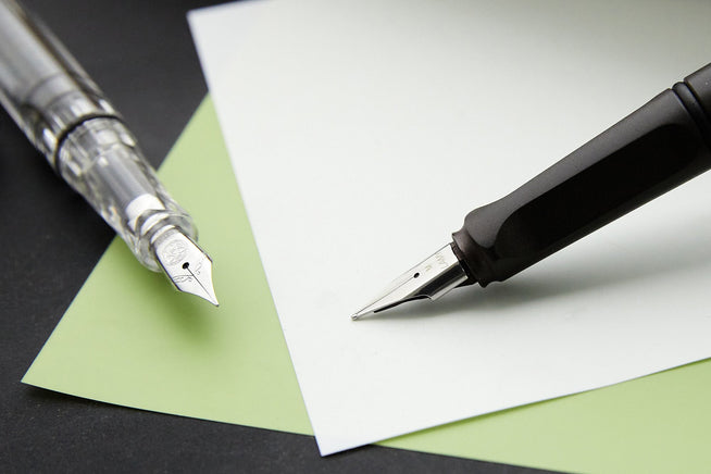 Two fountain pens touching mylar paper