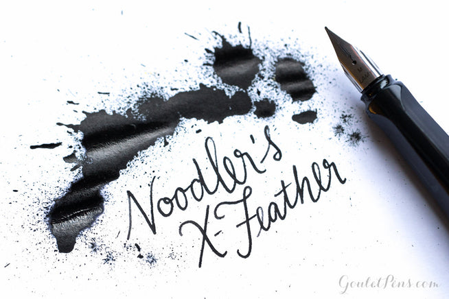 Noodler's X-Feather Black hand writing and ink splatter with uncapped LAMY safari