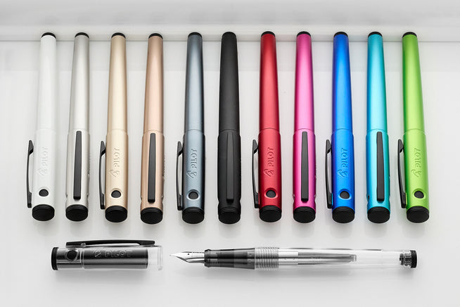Assorted Pilot Explorer fountain pens in assorted colors in a row on white background
