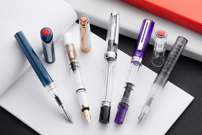 Assorted fountain pens by TWSBI capped and uncapped on a notebook