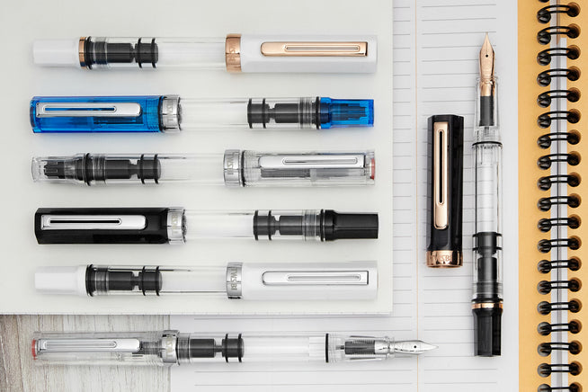 Assorted capped and uncapped TWSBI ECO's on notebooks
