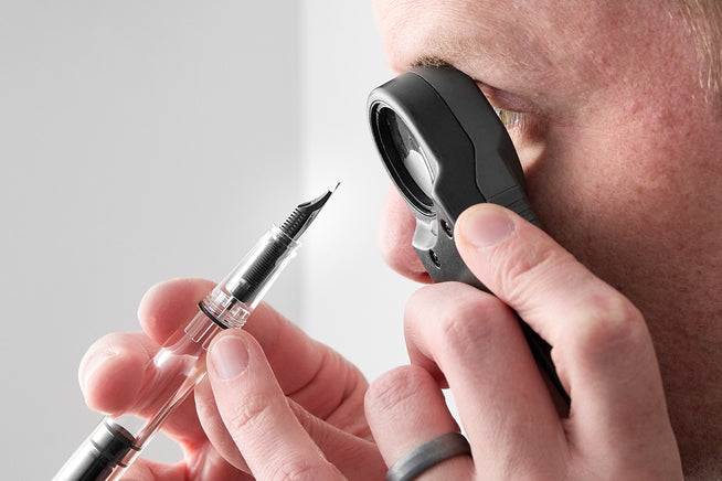 fountain pen, loupe, man holding pen