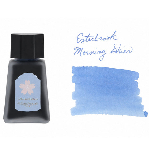 30ml bottle of Esterbrook Morning Skies ink next to a handwritten label and a swab swatch showing a soft sky blue color.