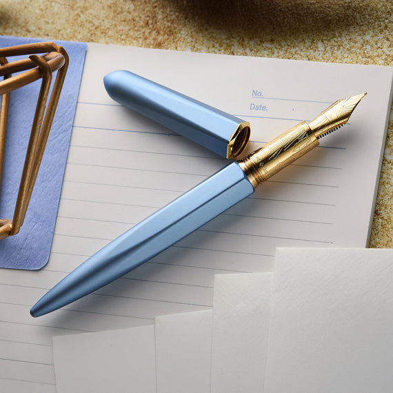 Blue and gold fountain pen on a piece of paper with a textured surface background